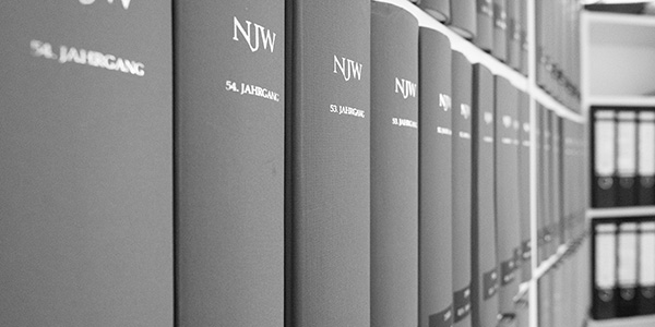 Eine Reihe grauer Bücher mit der Aufschrift NJW in einem Bücherregal.